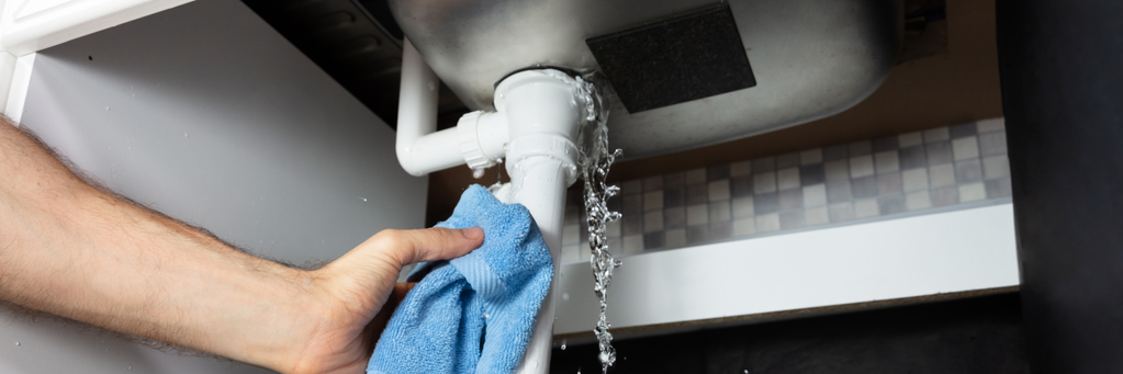 male hand's holding blue napkin under leakage pipe
