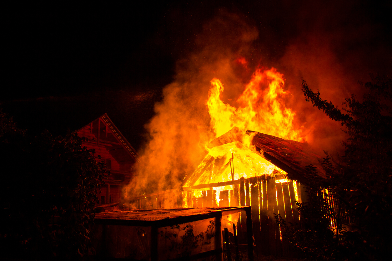 wooden house or barn burning on fire at night.