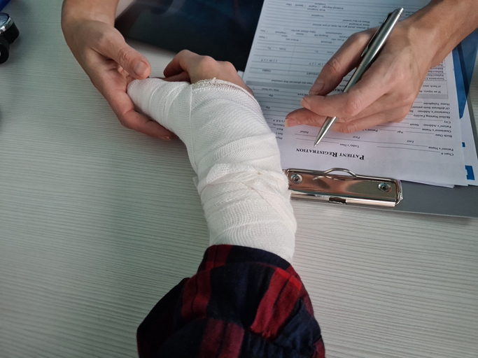 medical professional wrapping a patient injured hand while documenting care